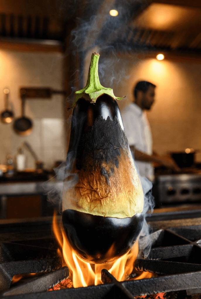 Aubergine carbonisée sur flamme vive au Quantum Isoraka, Antananarivo, illustrant la technique de fumage levantin pour caviar d'aubergine sans amertume.