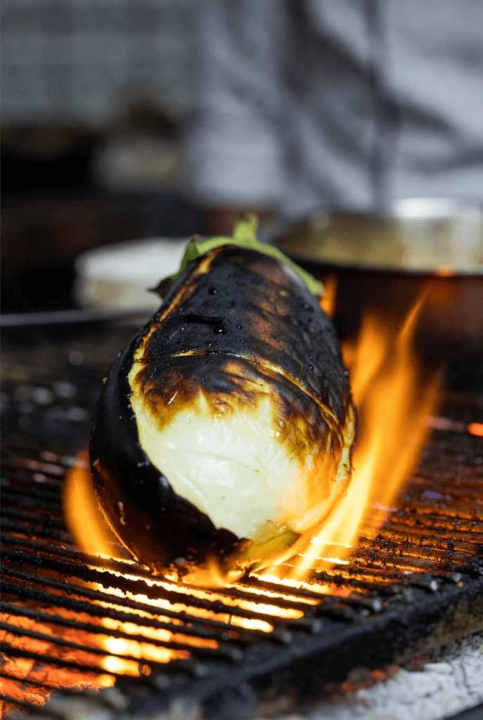 Grilled and blackened eggplant over an open flame, demonstrating Levantine smoking at Quantum Isoraka for a melting and healthy flesh.